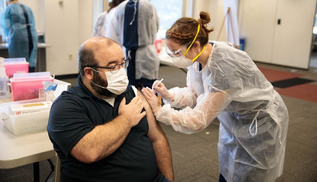 student administering flu vaccine